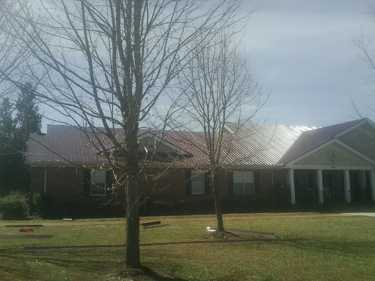 Red metal roof on a brick building seen from the front lawn in Pine Bluffs