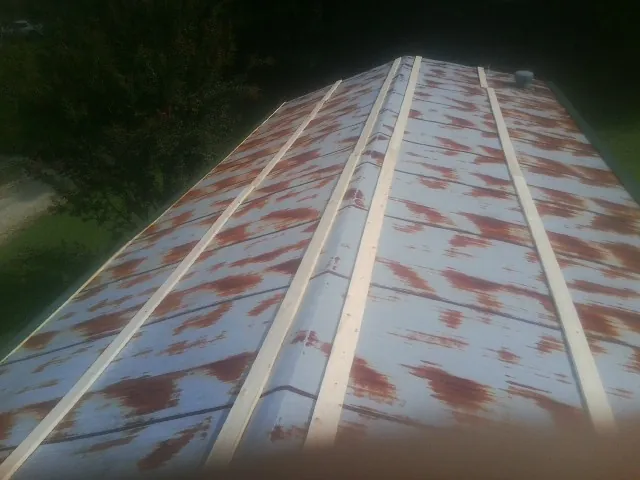 Rusted metal roof panels with new wood purlins before replacement — Storm Damage Roof Repair in Pine Bluffs by Roofing Brothers