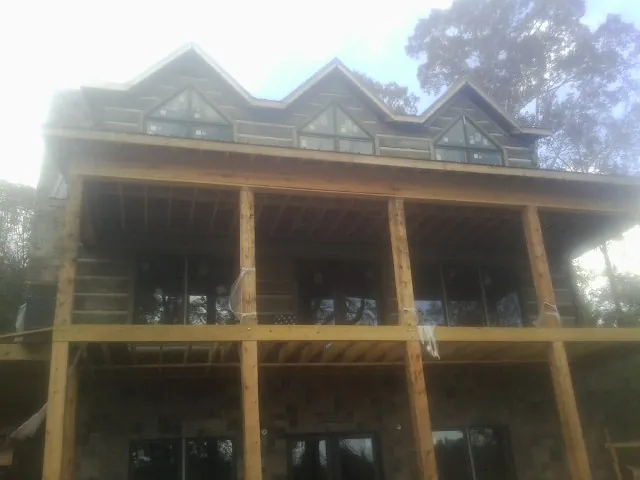 Dormers and porch framing on a large log home under construction — Roof Coating work by our crew in Pine Bluffs