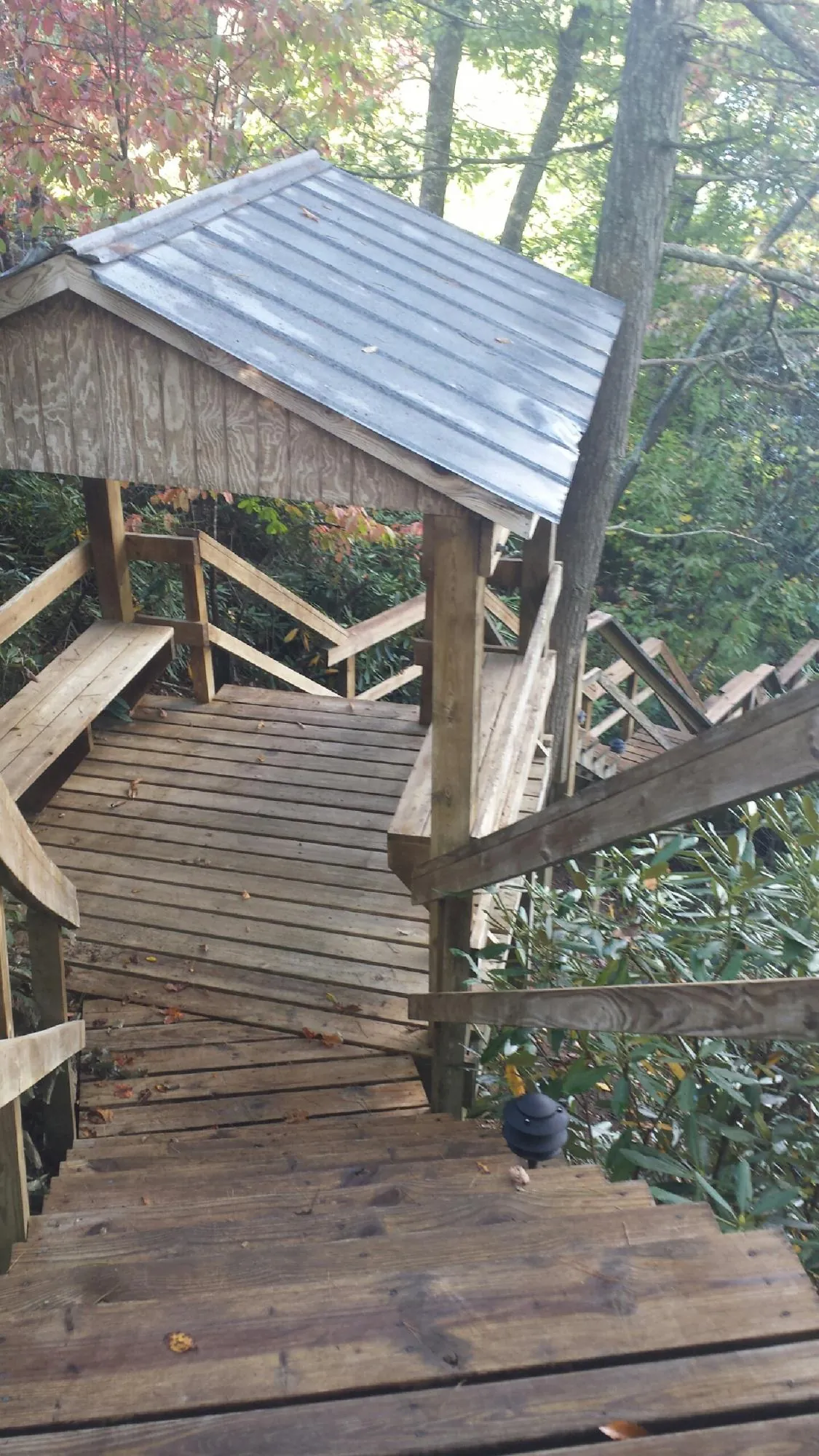 Metal roofed shelter over wooden steps on a wooded walkway — Skylight Repair & Installation work by our crew in Pine Bluffs