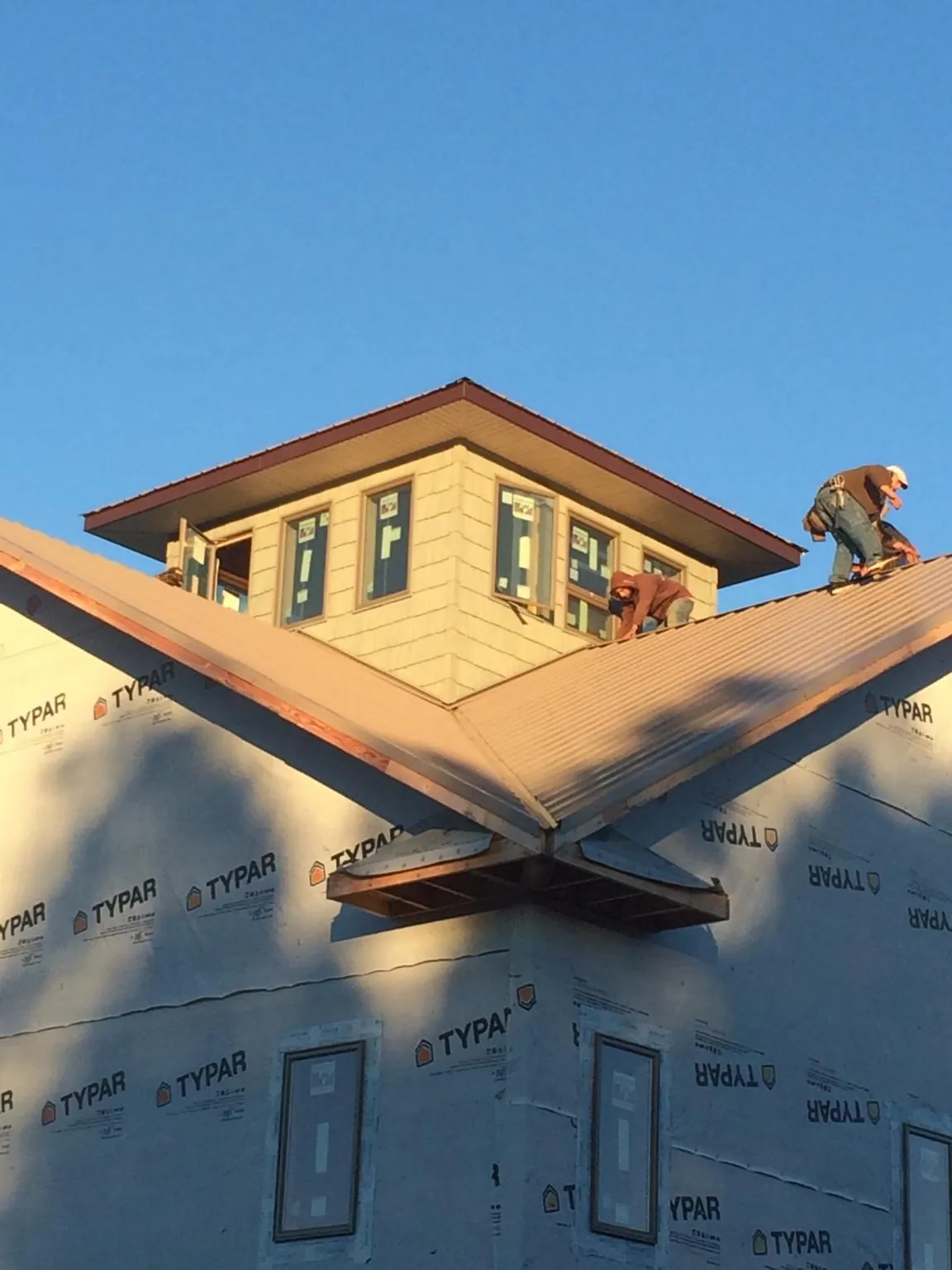 Roofers working around a rooftop cupola on a new metal roof at sunset — Roof Waterproofing in Pine Bluffs by Roofing Brothers